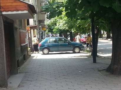 Баба паркира колата си на тротоара, за да си говори с позната